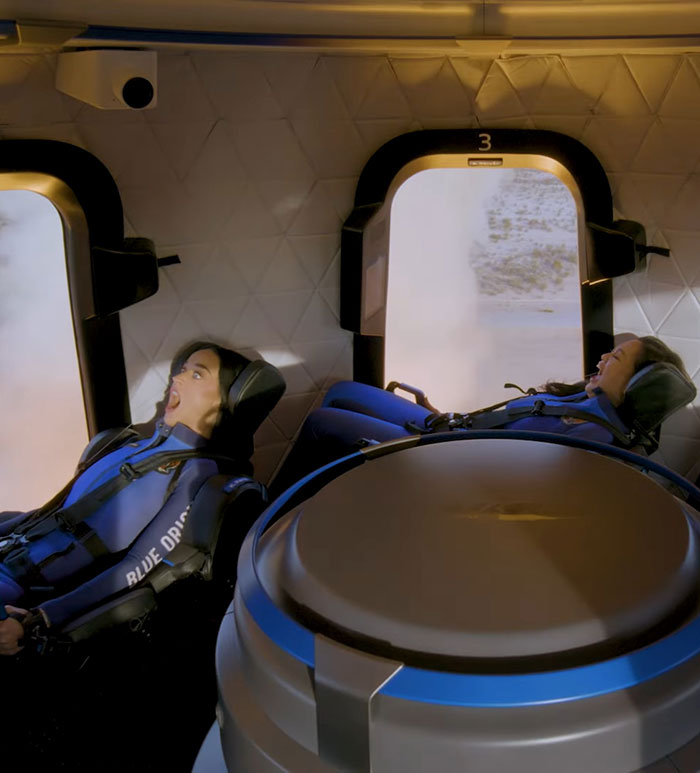 Two people in blue flight suits in a spacecraft interior, satirizing Blue Origin flight reactions. Two people in blue flight suits in a spacecraft interior, satirizing Blue Origin flight reactions.