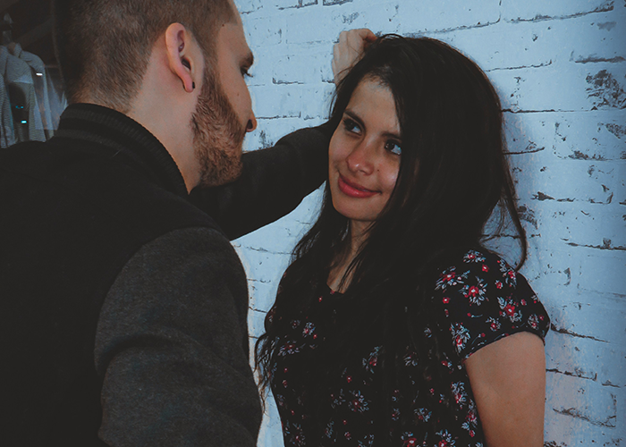 Man leaning against a wall talking to a woman in a floral dress. Man leaning against a wall talking to a woman in a floral dress.