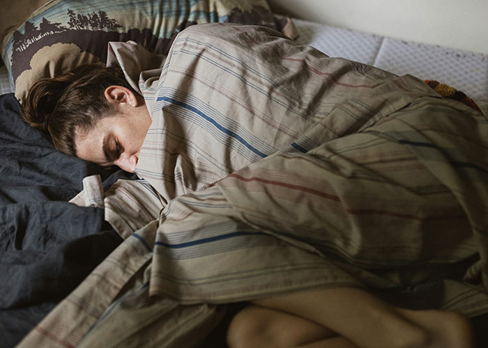 A woman lying in bed, wrapped in striped sheets, reflecting on a breakup. A woman lying in bed, wrapped in striped sheets, reflecting on a breakup.
