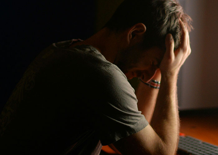 A man sitting in dim light, head in hands, reflecting on a breakup after 9 years. A man sitting in dim light, head in hands, reflecting on a breakup after 9 years.