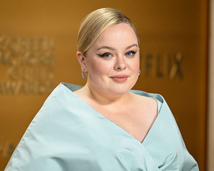 Bridgerton star in elegant gown at event with gold background, engaging in a public appearance. Bridgerton star in elegant gown at event with gold background, engaging in a public appearance.