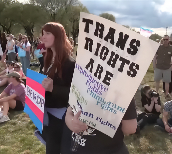Protesters holding signs advocating trans rights at a public gathering. Protesters holding signs advocating trans rights at a public gathering.