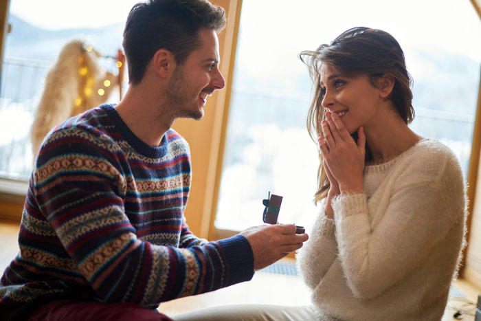 Man proposing to woman indoors, highlighting sibling wedding planning conflict. Man proposing to woman indoors, highlighting sibling wedding planning conflict.