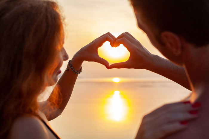 Couple creates heart shape with hands at sunset, symbolizing love and harmony despite sibling clash over wedding costs. Couple creates heart shape with hands at sunset, symbolizing love and harmony despite sibling clash over wedding costs.