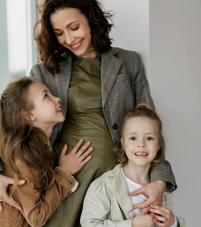 A smiling woman with two daughters, representing a spiteful accusation context. A smiling woman with two daughters, representing a spiteful accusation context.