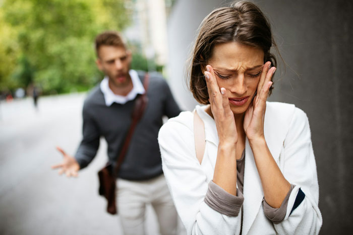 A woman looking distressed while a man argues in the background, highlighting a conflict involving CPS accusations. A woman looking distressed while a man argues in the background, highlighting a conflict involving CPS accusations.