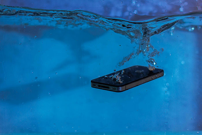 Smartphone sinking underwater in a pool, illustrating a lifeguard rescue and drowning emergency scenario.