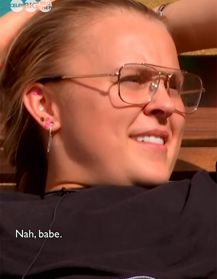 Person with sunglasses relaxing on 'Celebrity Big Brother' set, responding casually, "Nah, babe. Person with sunglasses relaxing on 'Celebrity Big Brother' set, responding casually, "Nah, babe.