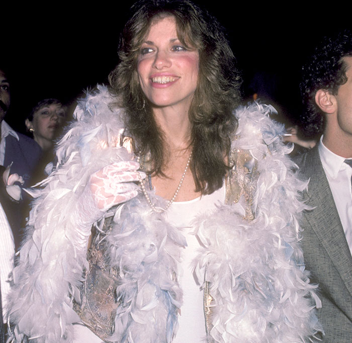 Smiling woman in a glamorous white feather outfit at an event, embodying Hollywood beauty style. Smiling woman in a glamorous white feather outfit at an event, embodying Hollywood beauty style.
