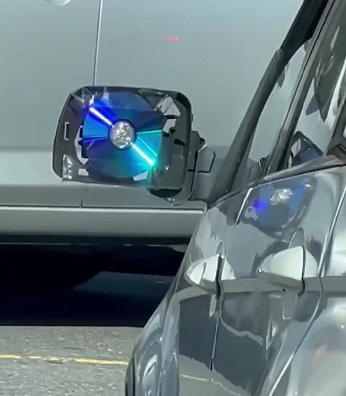 Car mirror repaired with a CD, showcasing a repair failure attempt.