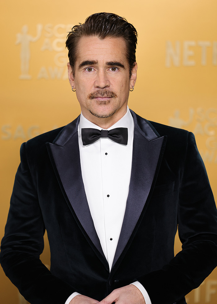 Actor in a black tuxedo with a bow tie at an awards event, standing against a gold backdrop. Actor in a black tuxedo with a bow tie at an awards event, standing against a gold backdrop.