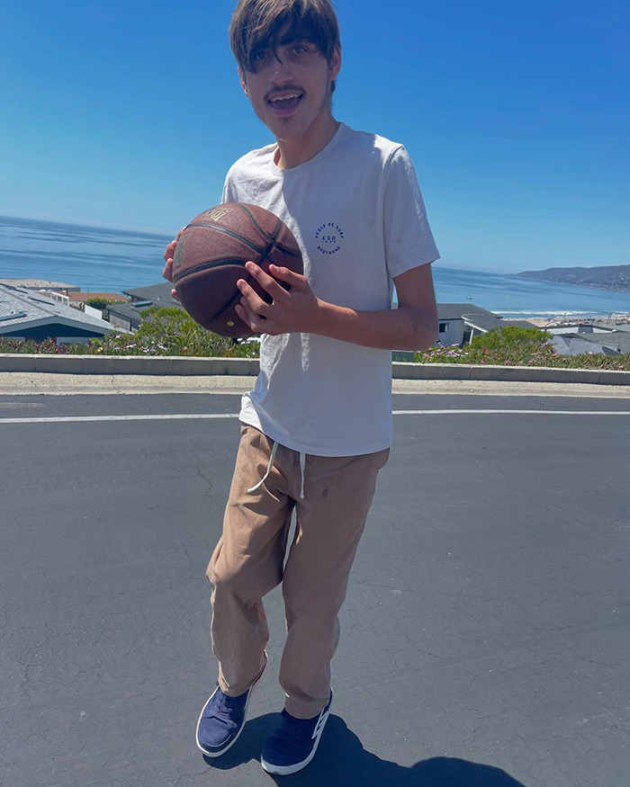 Young man holding a basketball by the ocean, related to Colin Farrell's 21-year-old disabled son and his care facility decision. Young man holding a basketball by the ocean, related to Colin Farrell's 21-year-old disabled son and his care facility decision.