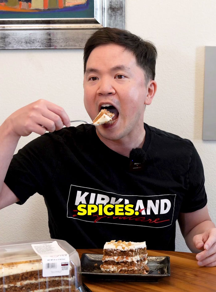 Man eating carrot cake with "Kirkland Signature" shirt, debating hidden ingredient in Costco dessert. Man eating carrot cake with "Kirkland Signature" shirt, debating hidden ingredient in Costco dessert.