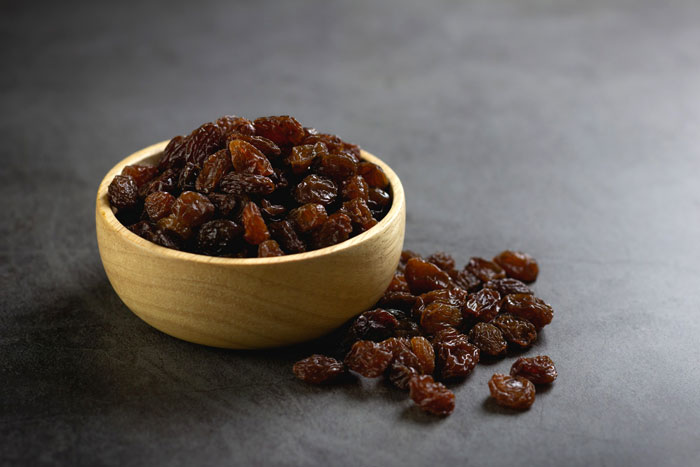 Wooden bowl filled with raisins, highlighting the debated ingredient in Costco's carrot cake recipe. Wooden bowl filled with raisins, highlighting the debated ingredient in Costco's carrot cake recipe.
