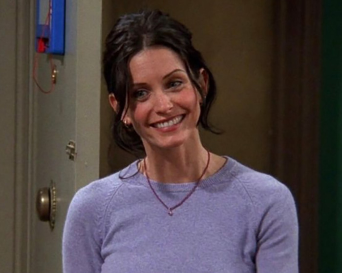 Courteney Cox smiling in a purple sweater during the "awkward encounter" reposted by Ellen DeGeneres. Courteney Cox smiling in a purple sweater during the "awkward encounter" reposted by Ellen DeGeneres.