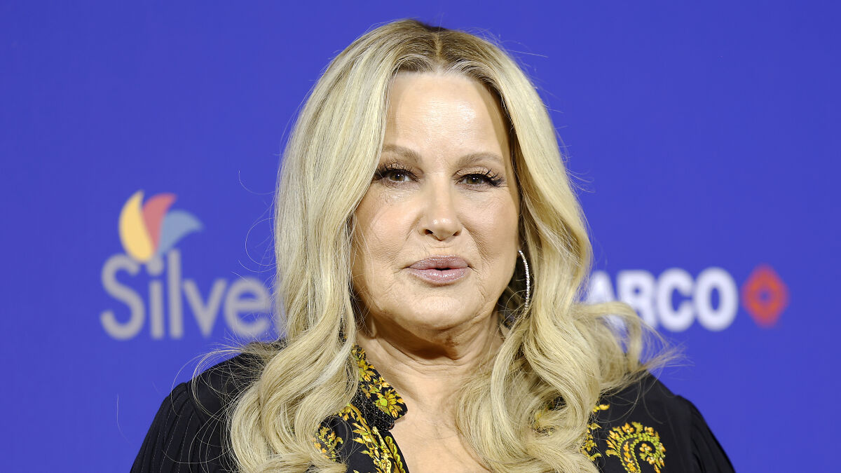 Jennifer Coolidge smiling at an event, with blonde hair and earrings, praised for her response about LGBTQ+ fans.