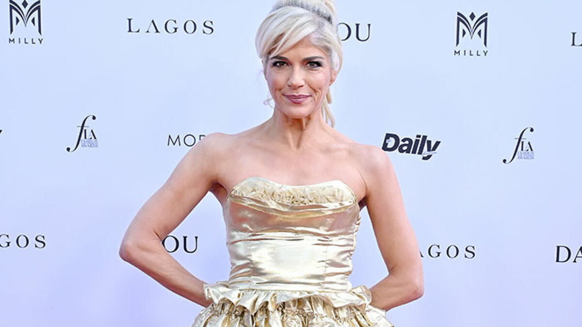 Selma Blair on the red carpet wearing a strapless gold dress, showcasing her amazing personality and kitten panties flash.