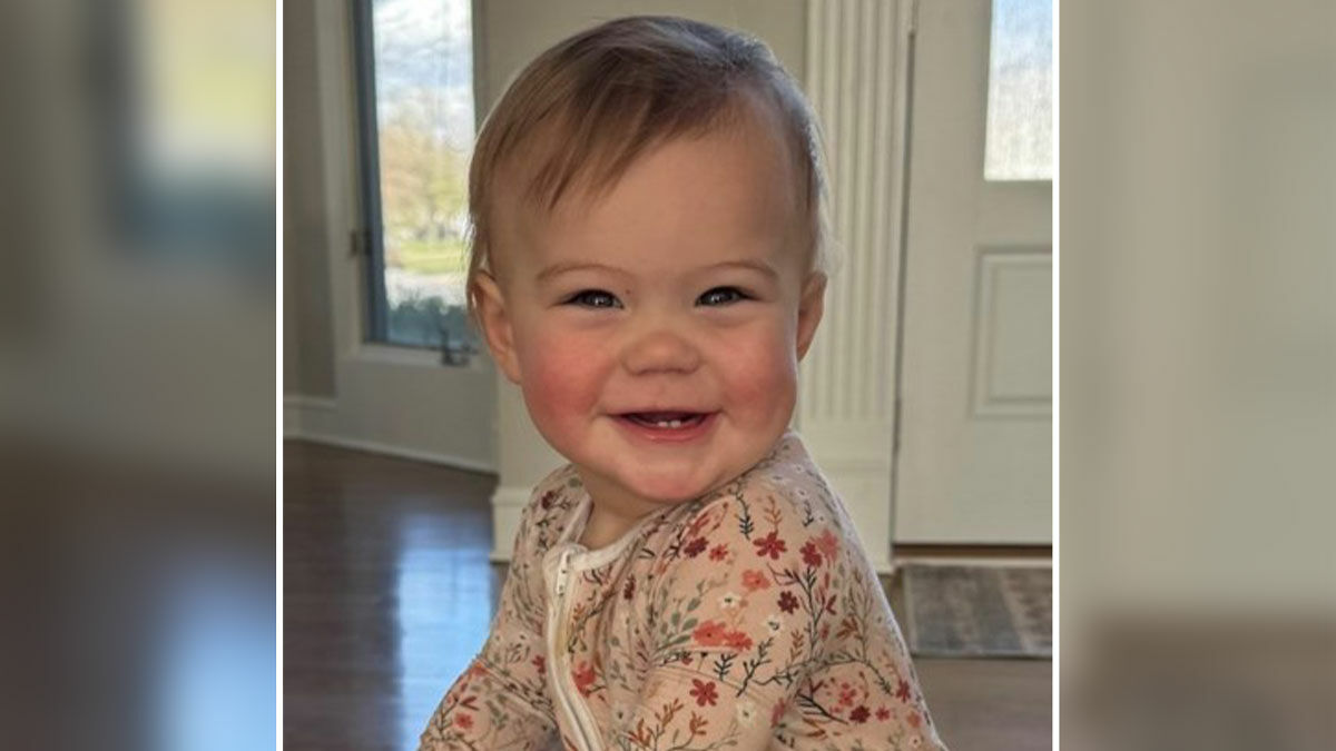 Smiling 12-month-old daughter of influencer, featured indoors with natural light, representing loss and mourning themes.