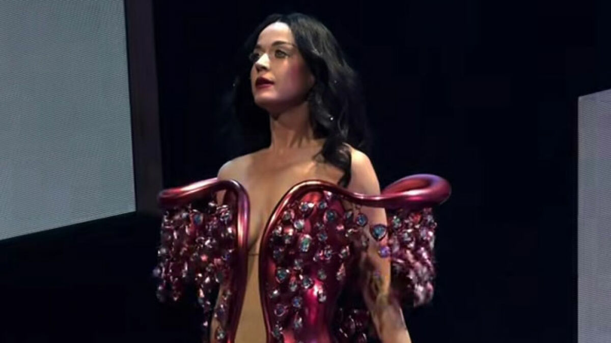 Katy Perry on stage wearing an elaborate red dress, responding to critics after Blue Origin space flight.