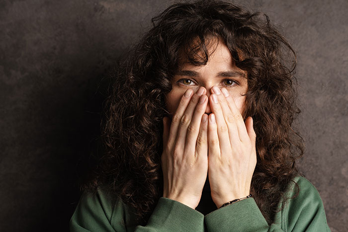 Woman covering mouth in panic, wearing a green shirt, illustrating a clever escape from a delusional client. Woman covering mouth in panic, wearing a green shirt, illustrating a clever escape from a delusional client.
