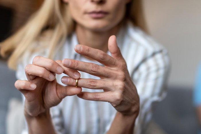 Woman removing wedding ring, symbolizing threat of divorce after dad defends bi daughter and family conflict over lifestyle.