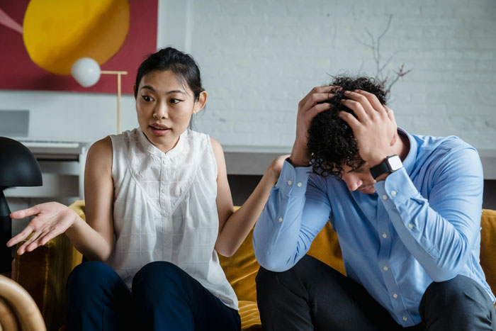 Couple having a tense discussion on a couch, illustrating conflict around family and defending a bi daughter’s lifestyle.