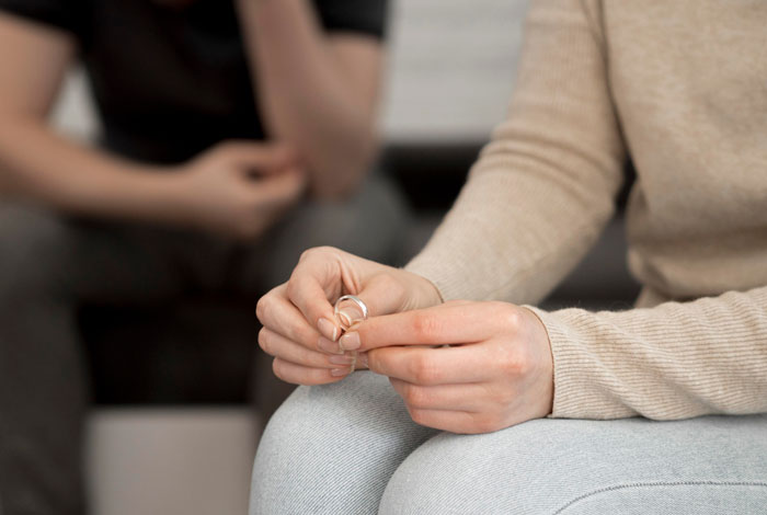 Person holding a wedding ring during a tense conversation about family conflict over bi daughter and lifestyle embarrassment.
