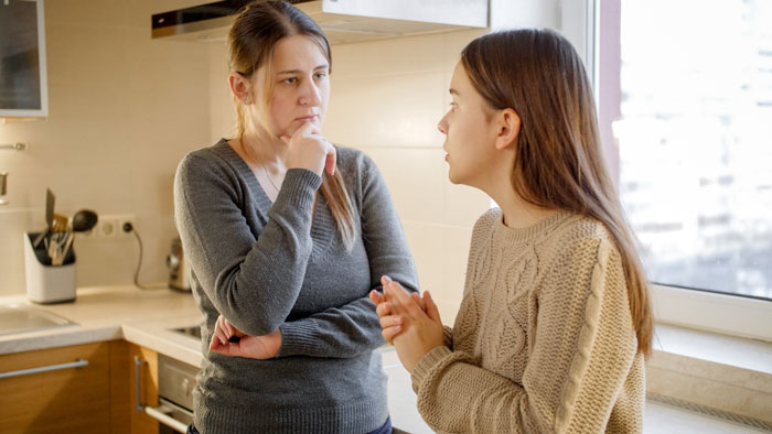 Woman and teen in kitchen having a serious discussion about stepdaughter moving back in. Woman and teen in kitchen having a serious discussion about stepdaughter moving back in.