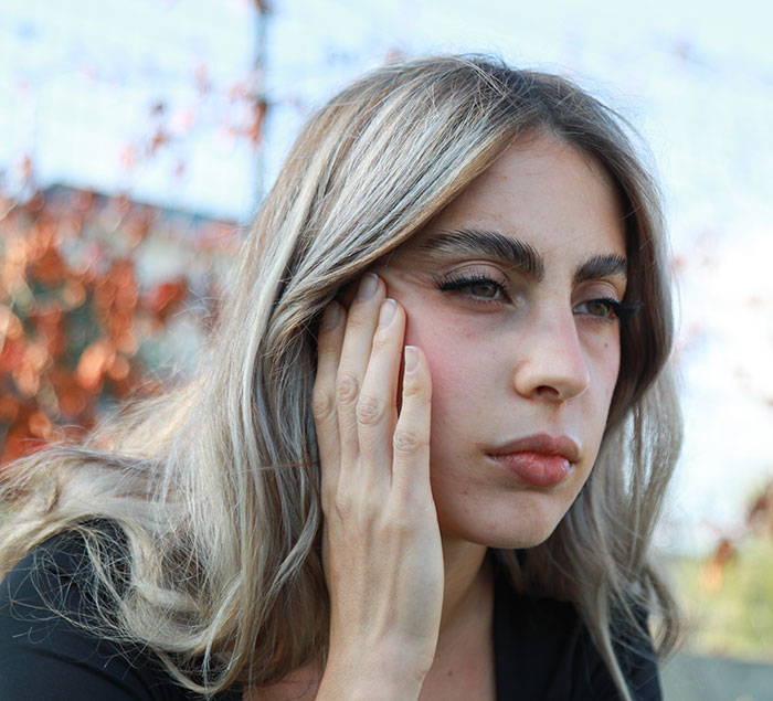 Woman looking concerned, hand on face, outdoors. Keywords: daughter, waste of space. Woman looking concerned, hand on face, outdoors. Keywords: daughter, waste of space.