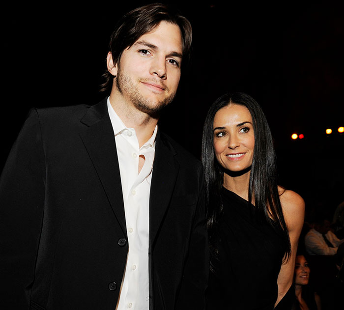 Ashton Kutcher and Demi Moore smiling at a public event in formal attire. Ashton Kutcher and Demi Moore smiling at a public event in formal attire.