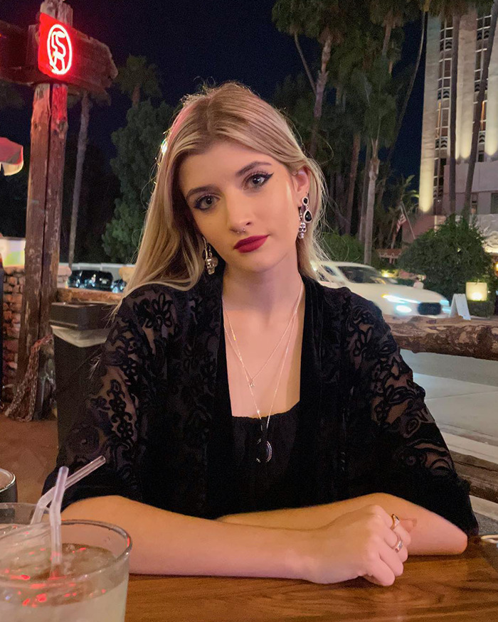 Young woman sitting outside at night, wearing black earrings and a lace top, related to Denise Richards' daughter's cosmetic surgeries. Young woman sitting outside at night, wearing black earrings and a lace top, related to Denise Richards' daughter's cosmetic surgeries.