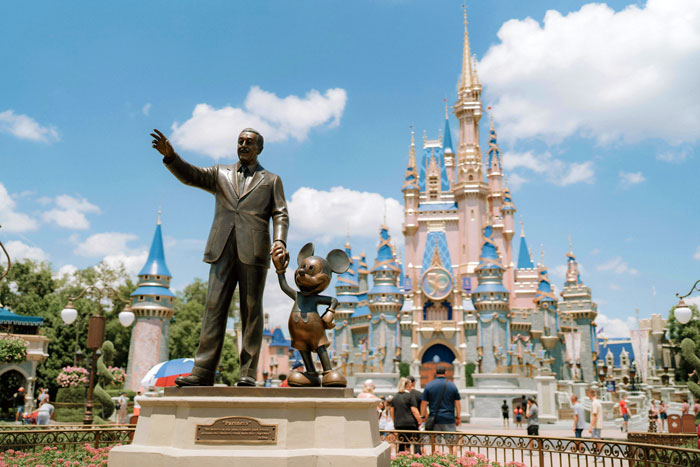 Statue of Walt Disney and Mickey Mouse at Disney park with castle, under a clear sky. Statue of Walt Disney and Mickey Mouse at Disney park with castle, under a clear sky.