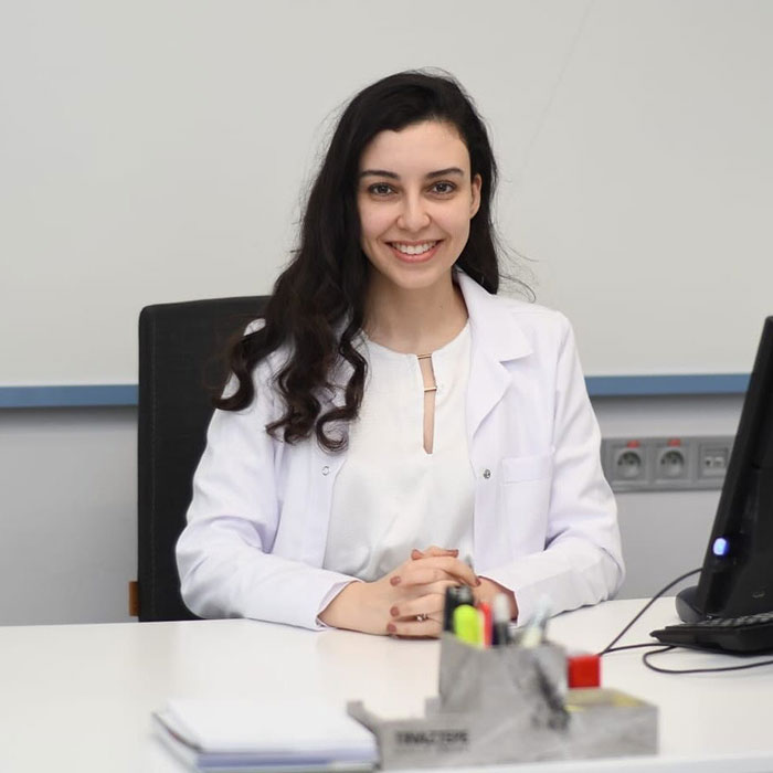 Smiling woman in a white coat sits at a desk, highlighting the impact of a botched nose job experience. Smiling woman in a white coat sits at a desk, highlighting the impact of a botched nose job experience.