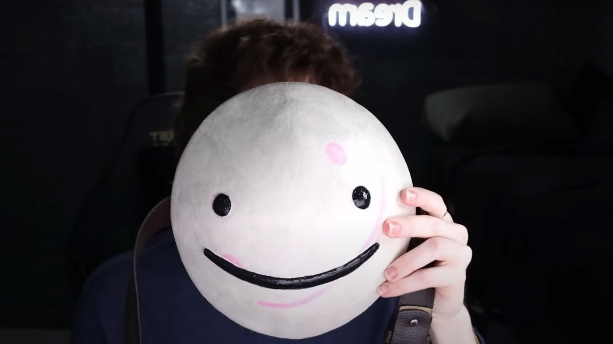 Person holding a round happy face mask in front of their face during a Dream face reveal video session.