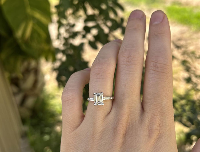 Hand wearing a pricey ring with a large rectangular gemstone, symbolizing millionaire neighbor's fiancée gift. Hand wearing a pricey ring with a large rectangular gemstone, symbolizing millionaire neighbor's fiancée gift.