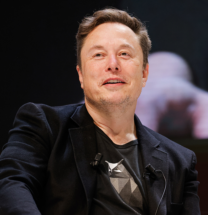 A person in a black jacket speaking at an event. A person in a black jacket speaking at an event.