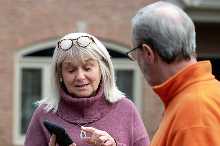Older woman showing something on a smartphone to an older man, illustrating wedding secrets turning into family drama. Older woman showing something on a smartphone to an older man, illustrating wedding secrets turning into family drama.