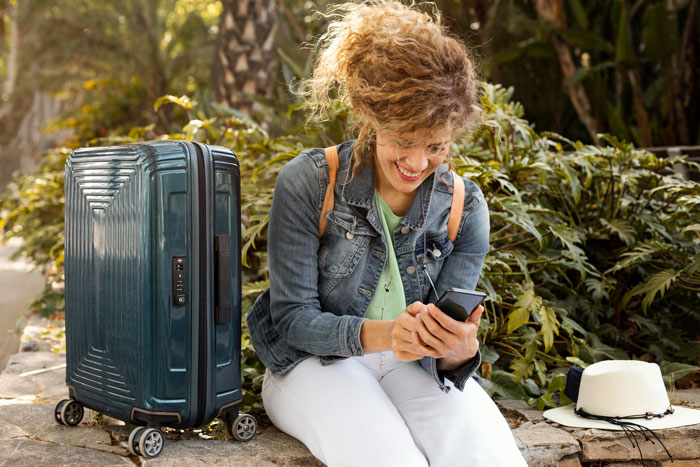 Bride smiling while checking phone outdoors with suitcase nearby, reflecting wedding secrets and drama involving parents. Bride smiling while checking phone outdoors with suitcase nearby, reflecting wedding secrets and drama involving parents.