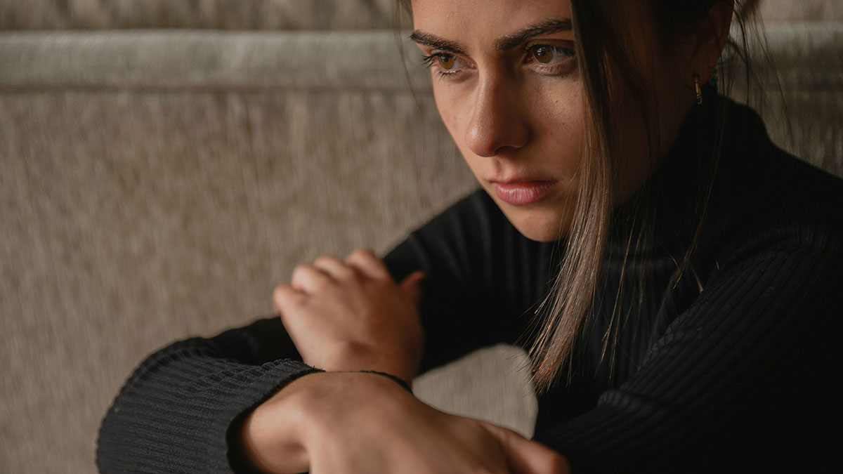 Bride in black sweater looking sad and reflective, capturing wedding secrets and family drama emotions.