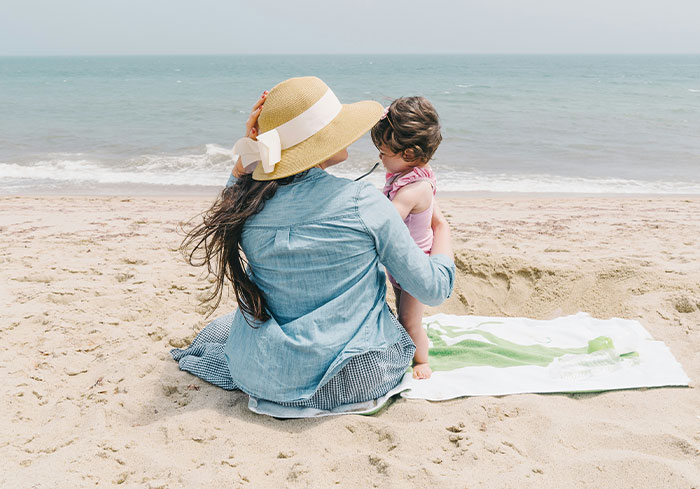 Woman sitting on the beach with a child, contemplating Easter vacation plans without her sister. Woman sitting on the beach with a child, contemplating Easter vacation plans without her sister.