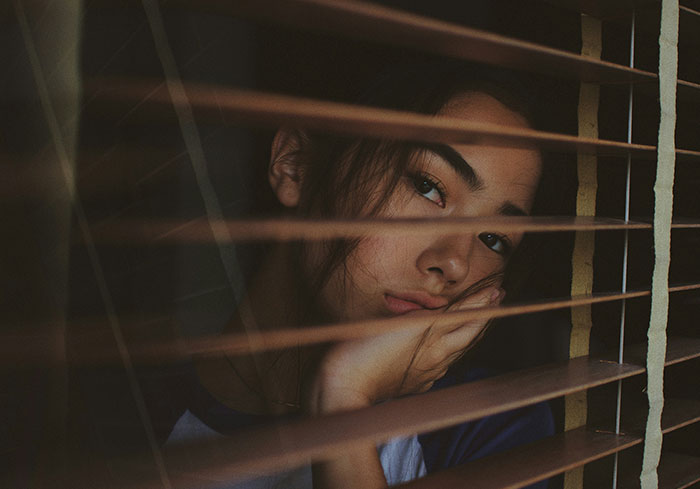 Woman thinking, looking through window blinds, contemplating Easter vacation decision. Woman thinking, looking through window blinds, contemplating Easter vacation decision.
