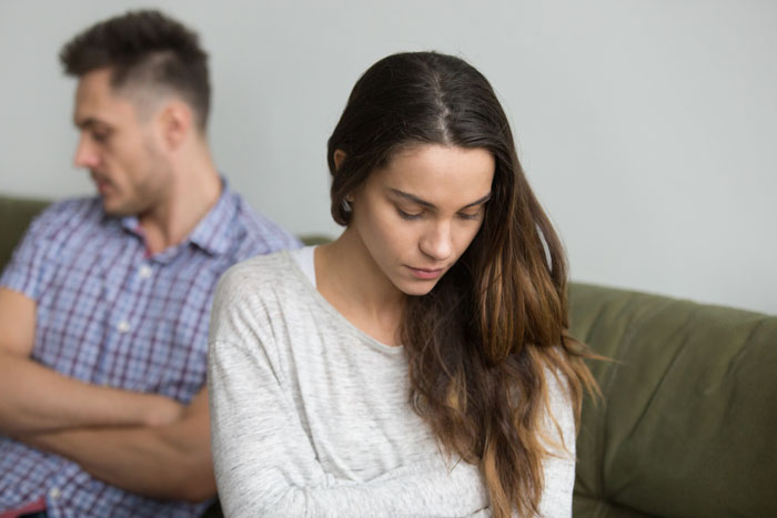A couple sitting apart on a couch, showing tension before Valentine's breakup. A couple sitting apart on a couch, showing tension before Valentine's breakup.