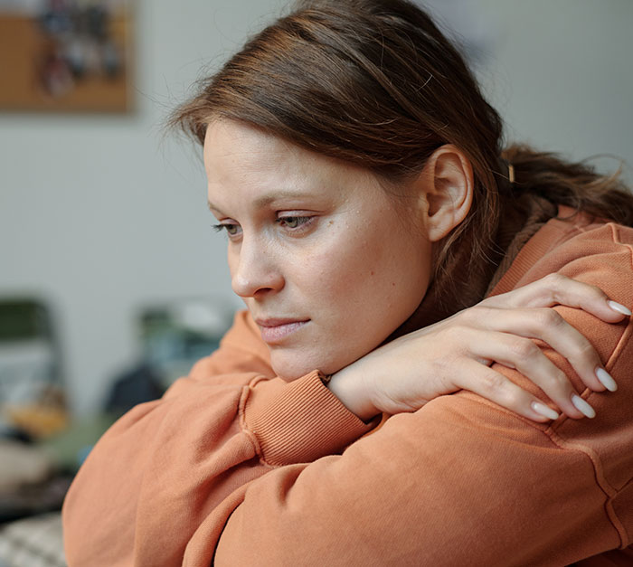 Woman reflecting, wearing an orange sweater, in a contemplative mood after exposing her partner's scheme. Woman reflecting, wearing an orange sweater, in a contemplative mood after exposing her partner's scheme.
