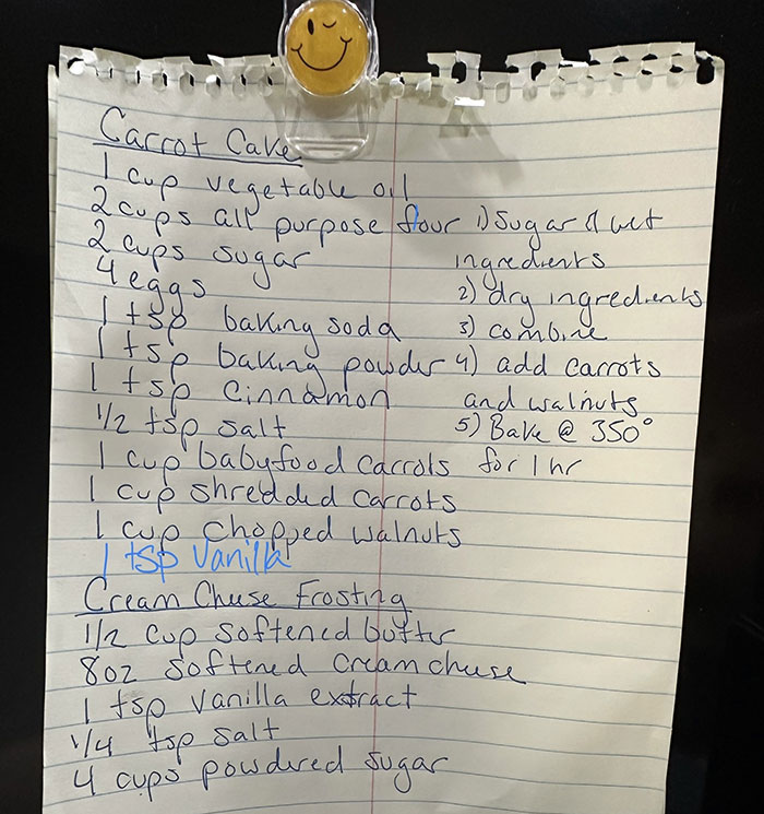 Handwritten carrot cake recipe on lined paper with ingredients and baking instructions clipped with a smiley face clip. Handwritten carrot cake recipe on lined paper with ingredients and baking instructions clipped with a smiley face clip.