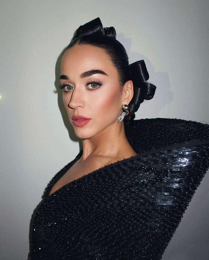 A person with styled hair and a glamorous black outfit poses against a plain backdrop, related to limited edition doll controversy. A person with styled hair and a glamorous black outfit poses against a plain backdrop, related to limited edition doll controversy.