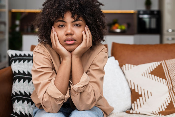 Woman sitting on a sofa, looking contemplative, with focus on relationship dynamics. Woman sitting on a sofa, looking contemplative, with focus on relationship dynamics.