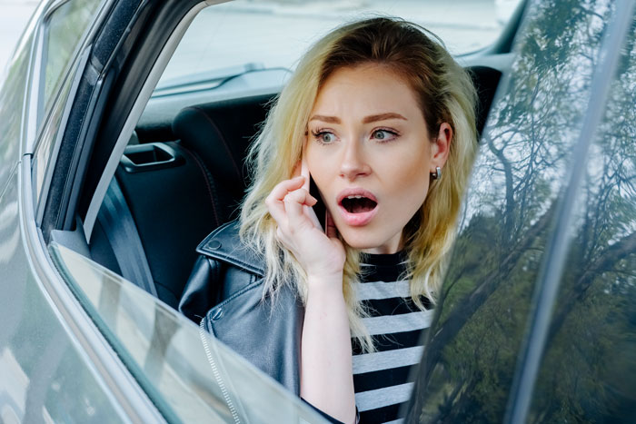Young woman in car, looking shocked, on phone discussing weird behavior with motives. Young woman in car, looking shocked, on phone discussing weird behavior with motives.