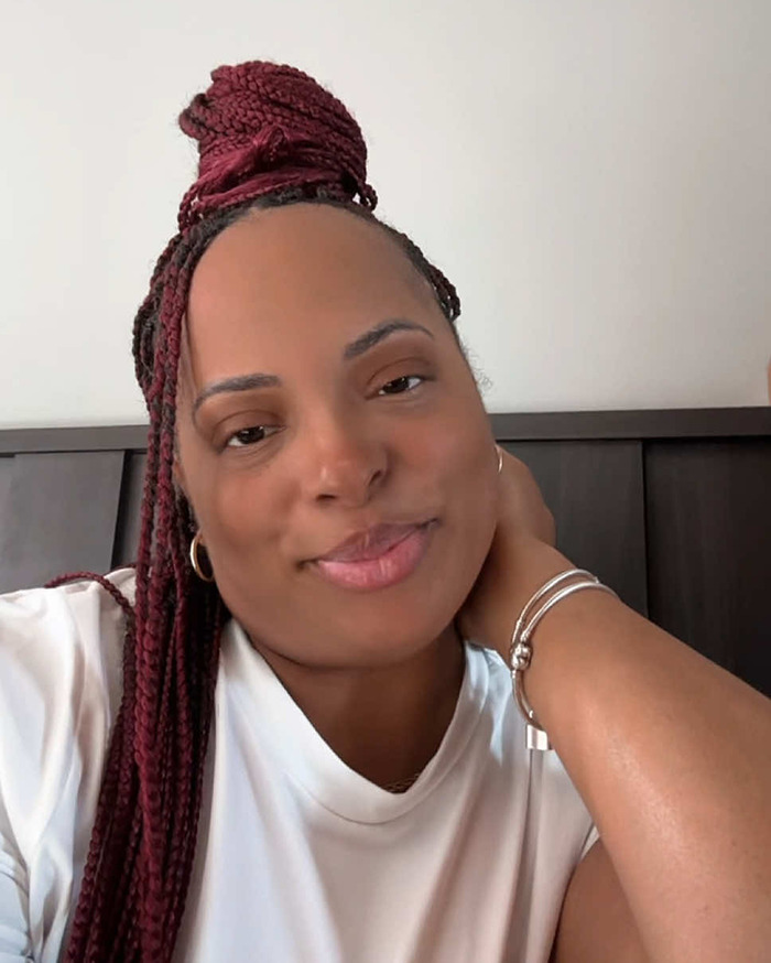 Smiling woman with braided hair and white shirt, sitting indoors. Smiling woman with braided hair and white shirt, sitting indoors.