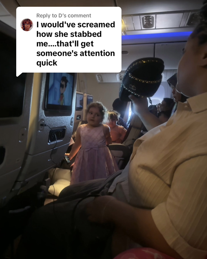 Child in a pink dress stands in airplane aisle, onboard scene with passengers seated and overhead comment about a stabbing incident. Child in a pink dress stands in airplane aisle, onboard scene with passengers seated and overhead comment about a stabbing incident.