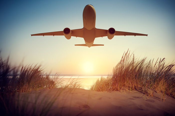 Airplane flying over a sandy beach at sunset, symbolizing travel and window seats. Airplane flying over a sandy beach at sunset, symbolizing travel and window seats.